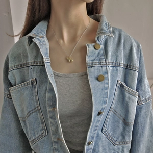 Detailed view of a gold elephant pendant necklace worn over a denim jacket