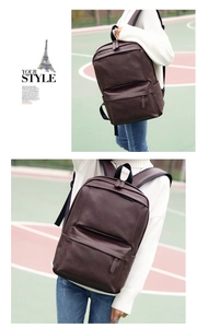 Outdoor view of a man wearing a dark brown PU leather backpack with front zipper detail