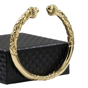 Detailed close-up of 18K gold-plated open bangle with twisted texture on a black box