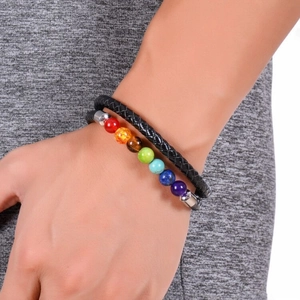 Dettaglio di 7 pietre chakra e bracciale in pelle intrecciata nera sul polso di un modello
