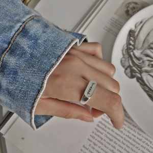 Close-up of silver sterling ring featuring hand-engraved breeze script on a polished band