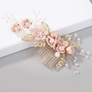 Détail de fleurs en tissu rose et feuilles dorées sur un peigne de mariée élégant