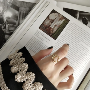 Dettaglio di mano che indossa un anello a stella dorato con elegante manica ricamata