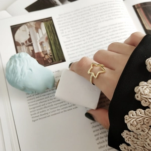 Primo piano artistico di un anello a stella dorato su una modella con libro