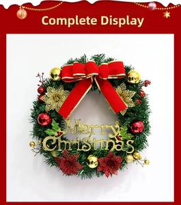 Close-up of a Christmas wreath with red bows, gold glitter flowers, and Merry Christmas sign