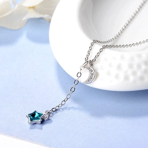 Elegant silver moon and blue star pendant necklace for women on a white ceramic plate