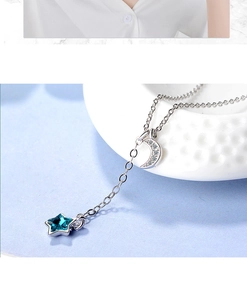 Macro view of blue star and crescent moon pendants on silver chain necklace