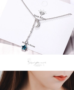 Detail view of blue star and silver moon pendant necklace worn on neck and packaging