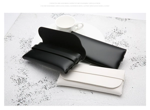 Detail of premium black and white leather eyewear pouches on marble texture surface
