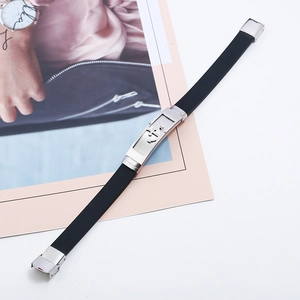Men's black silicone bracelet with a silver anchor motif metal clasp on a magazine background