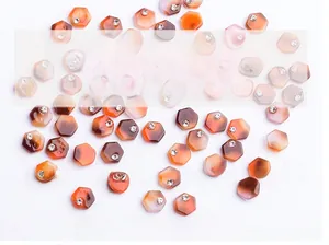 Close-up of hexagonal orange marble agate nail charms with centered rhinestone accents