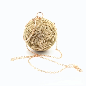 Close-up of golden spherical evening bag with rhinestones and metal ring handle