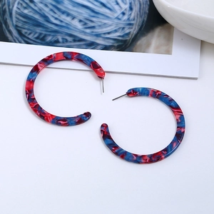 Detailed close-up of C-shaped resin earrings with red and blue marble texture design