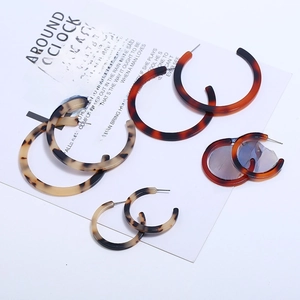 Detail of assorted tortoise shell acrylic C-shape hoop earrings on a white display card
