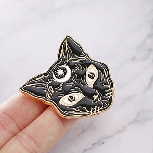 Detail of a small black enamel cat brooch with gold crescent moon and star patterns