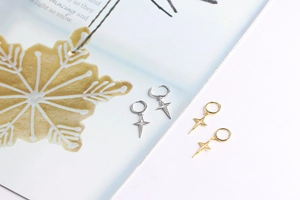 Detailed view of silver and gold star drop earrings on a magazine background