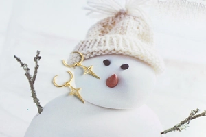 Detailed close-up of golden S925 sterling silver star hoop earrings in a cozy winter setting