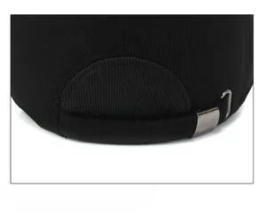 Detailed close-up of adjustable strap with metal buckle on black corduroy baseball cap