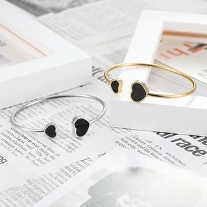 Detail view of heart-shaped stainless steel open bangles in gold and silver finish
