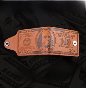 Detail of vintage brown leather wallet with embossed US dollar bill pattern and metal snap