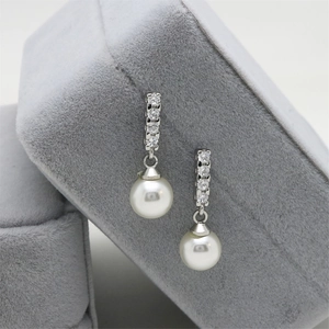 Detail view of silver pearl earrings with zircons on a grey velvet jewelry box display