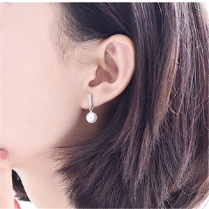 Detailed close-up of a high-quality white pearl drop earring with sparkling accents