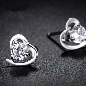 Macro detail of heart-shaped silver earrings with sparkling round zircon stone