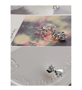 Macro shot of silver bow earrings with zircon stones on a clean white background