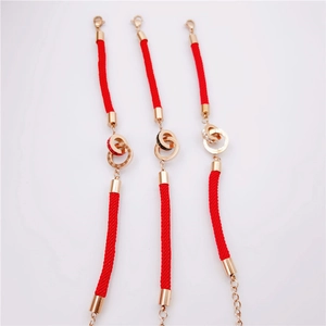 Detail of rose gold double rings with Roman numerals and crystals on red cords