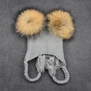 Gray knit trapper hat for children featuring double faux fur pom-poms and braided ties