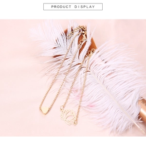 Vue détaillée de bracelets lotus et cœur dorés posés sur une plume blanche élégante
