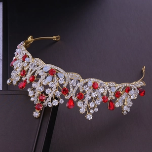 Detail view of gold bridal tiara with red and clear crystals on a dark background