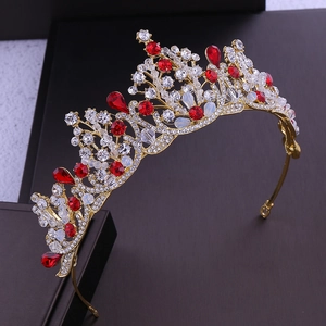 Detailed close-up of a bridal crown with red and clear rhinestones on a gold metal base