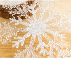 Vue macro d'un flocon de neige en acrylique transparent avec paillettes sur bois