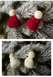 Mini knitted Christmas hats on frosted pine branches for festive holiday tabletop decor