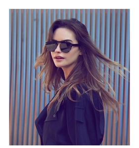 Close-up of black oversized sunglasses with metal accents worn in a stylish street shoot