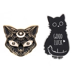 Detail of black enamel cat brooches with gold crescent moon and Good Luck lettering