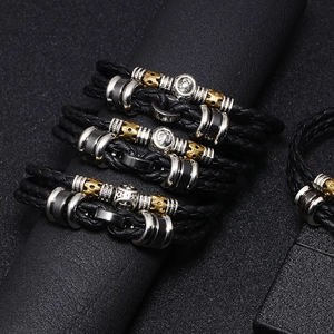Braided black leather bracelets with metallic zodiac charms on a display stand