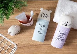 Detail of portable light blue and purple cartoon animal travel toothbrush cups on wooden desk