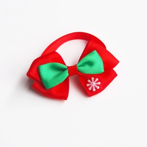Detail view of a red and green Christmas pet bow tie with snowflake pearl ornament