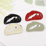 Detail of four colorful enamel cat brooches on a notebook page background