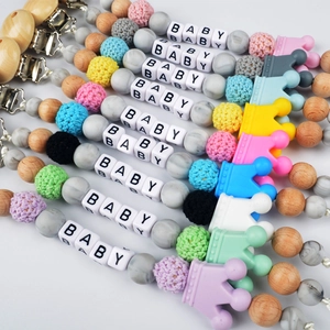 Colorful silicone and wooden baby pacifier clips with crown and letter beads on white background