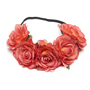 Close-up of artificial coral and peach roses on an elastic floral bridal headband