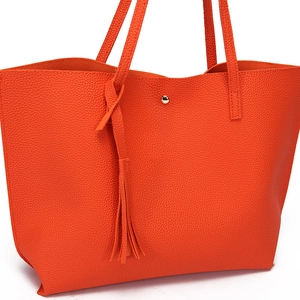 Close-up of orange litchi grain tote bag with tassel ornament and magnetic buckle