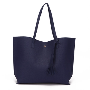 Close-up of litchi textured navy blue tote bag with gold buckle and tassel detail