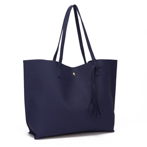 Detail of navy blue pebble faux leather tote with tassel charm and gold magnetic closure