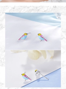 Macro detail of bird-shaped stud earrings featuring colorful enamel and silver needles