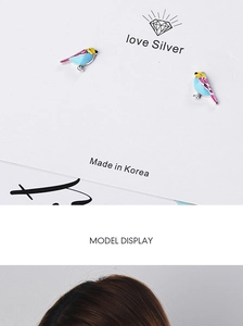 Detailed view of sky blue bird stud earrings with colorful enamel accents on display