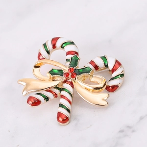 Macro detail of enamel candy cane brooch with festive green holly leaves and gold bow