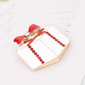 Detailed gift box brooch with red crystals, a bow and gold-plated enamel finish
